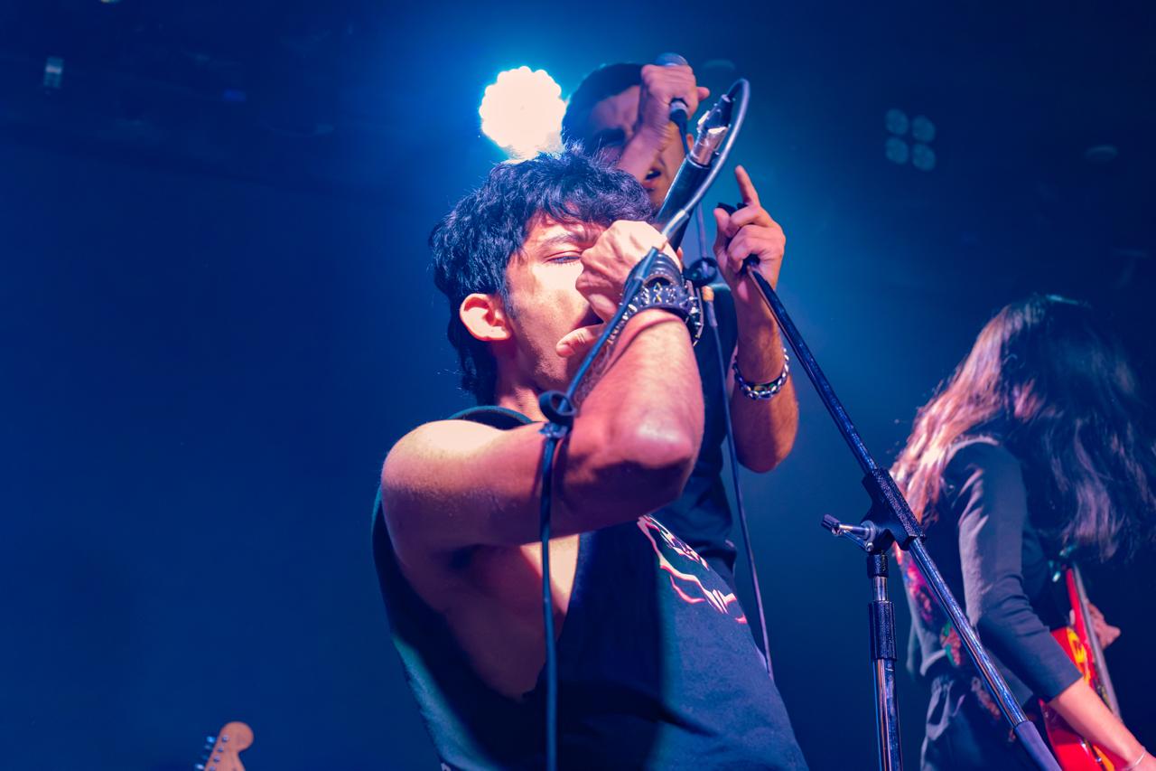 Adithya singing into a microphone on stage